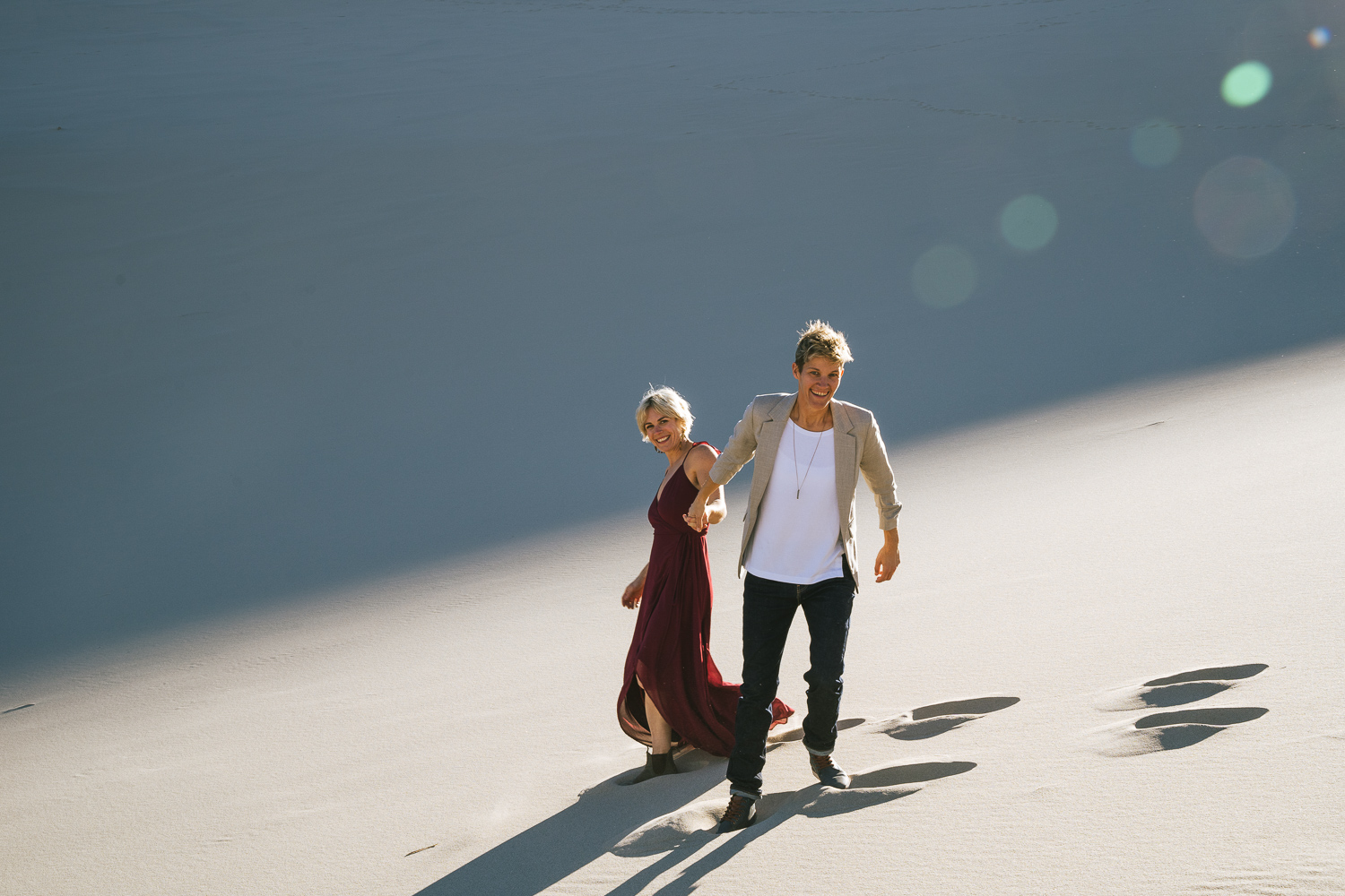 Two brides in the Death Valley Sand dunes, with a bohemian style flowy red dress