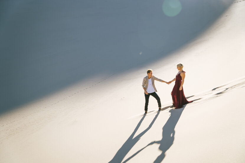 Two brides in the Death Valley Sand dunes, with a bohemian style flowy red dress