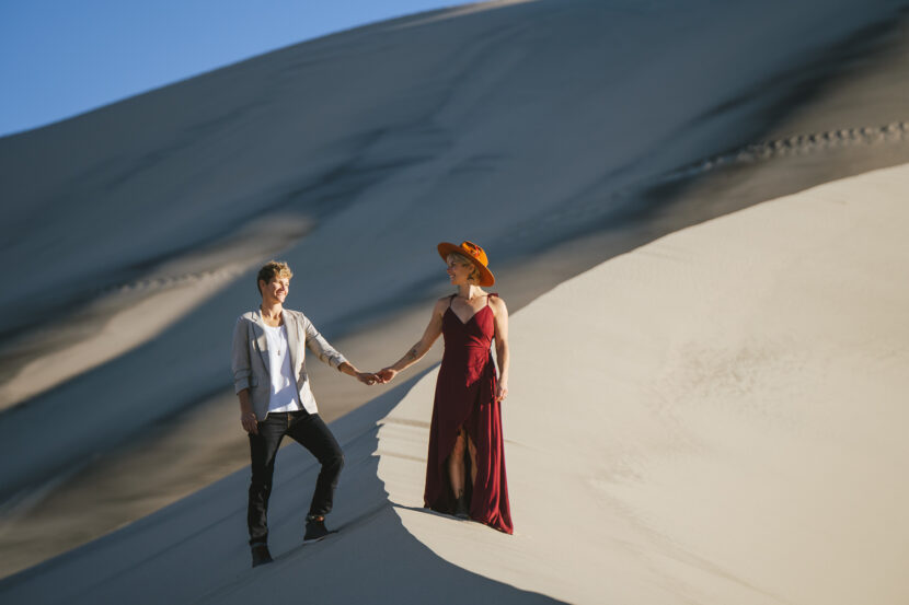 Two brides in the Death Valley Sand dunes, with a bohemian style flowy red dress