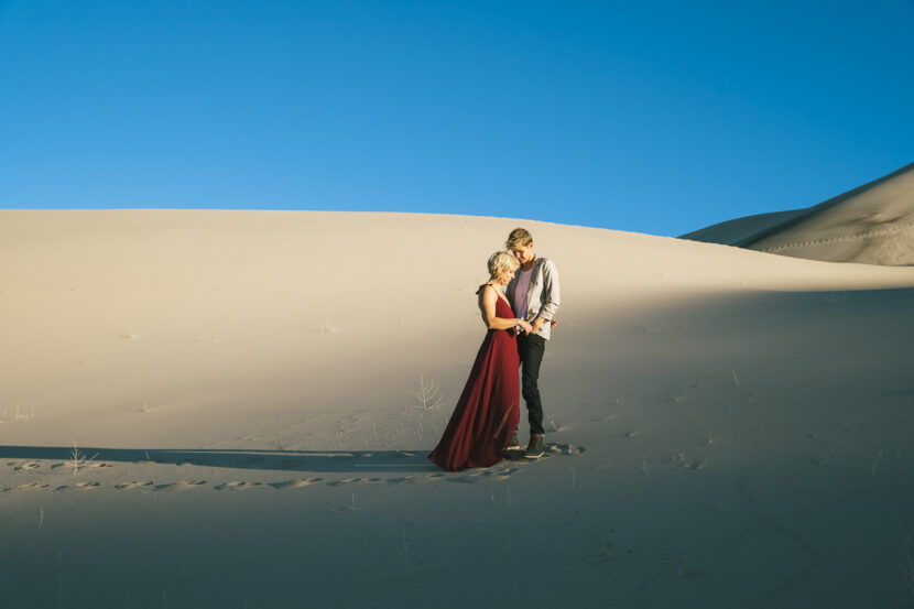 Two brides in the Death Valley Sand dunes, with a bohemian style flowy red dress