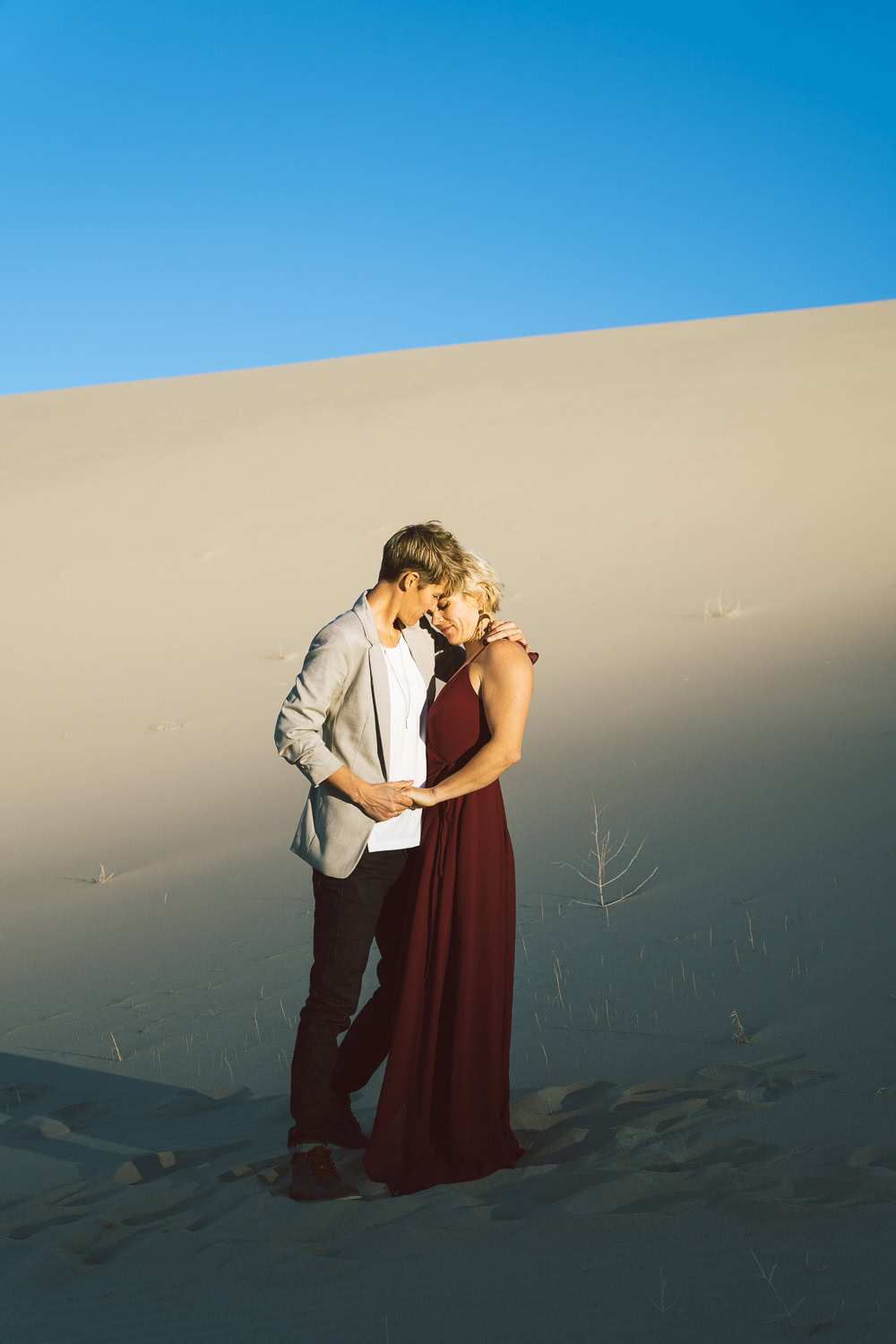 Two brides in the Death Valley Sand dunes, with a bohemian style flowy red dress