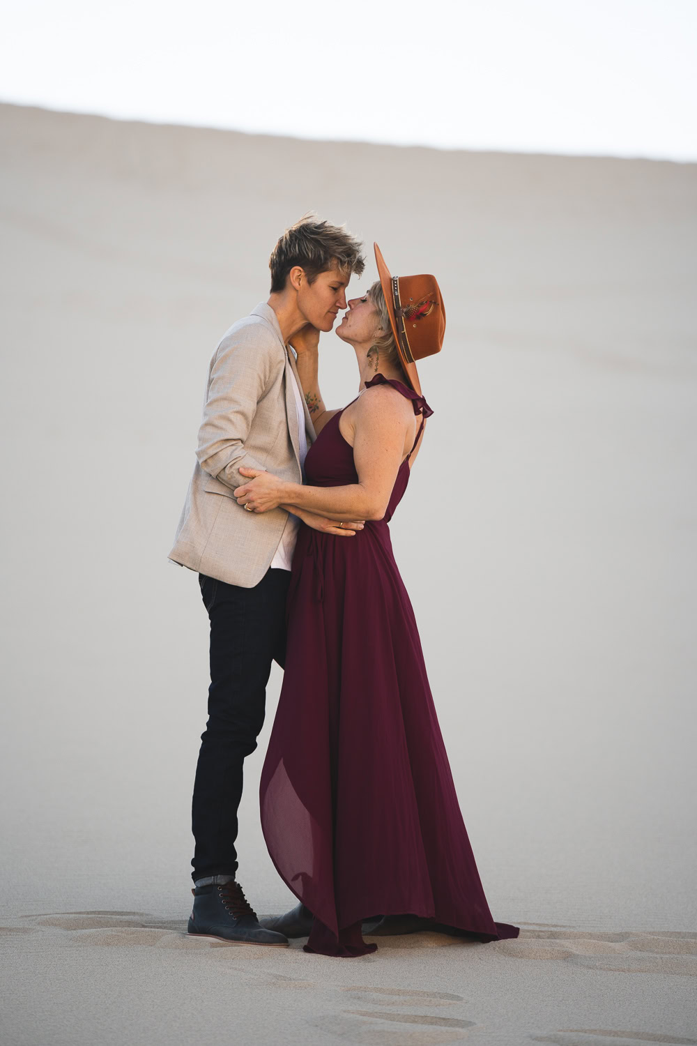 Two brides in the Death Valley Sand dunes, with a bohemian style flowy red dress