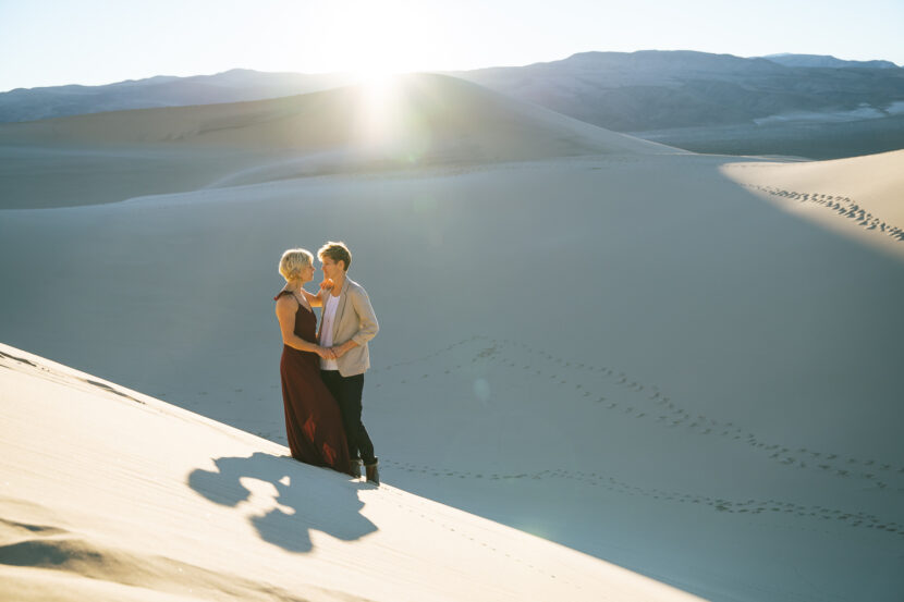 Two brides in the Death Valley Sand dunes, with a bohemian style flowy red dress