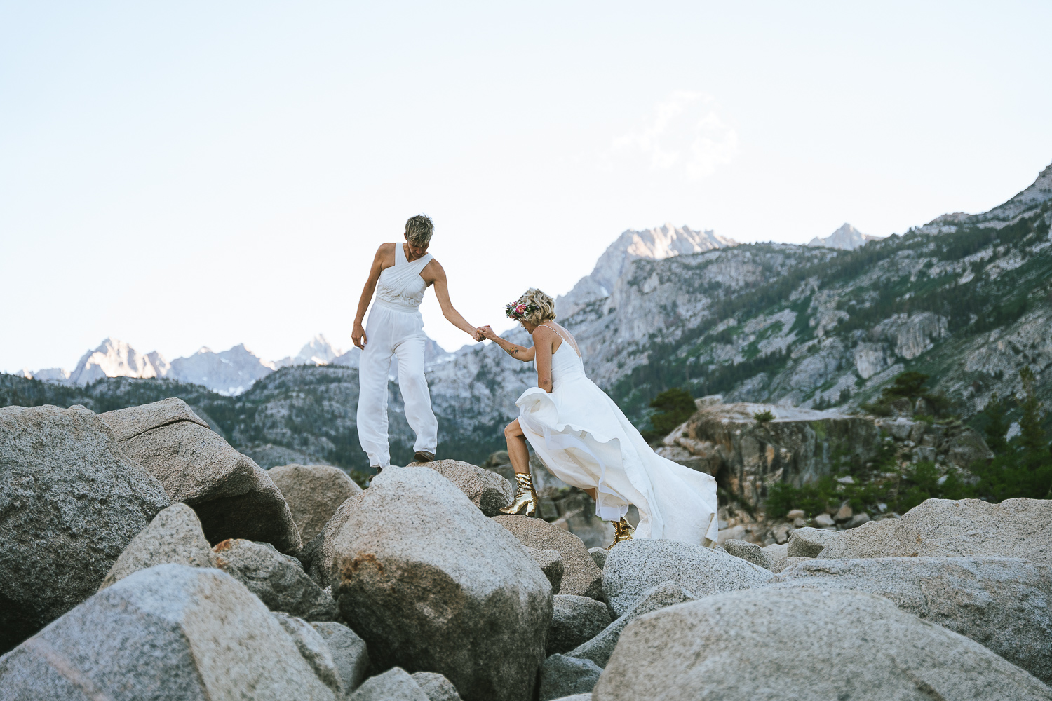 Two brides scrambling on boulders at lake sabrina
